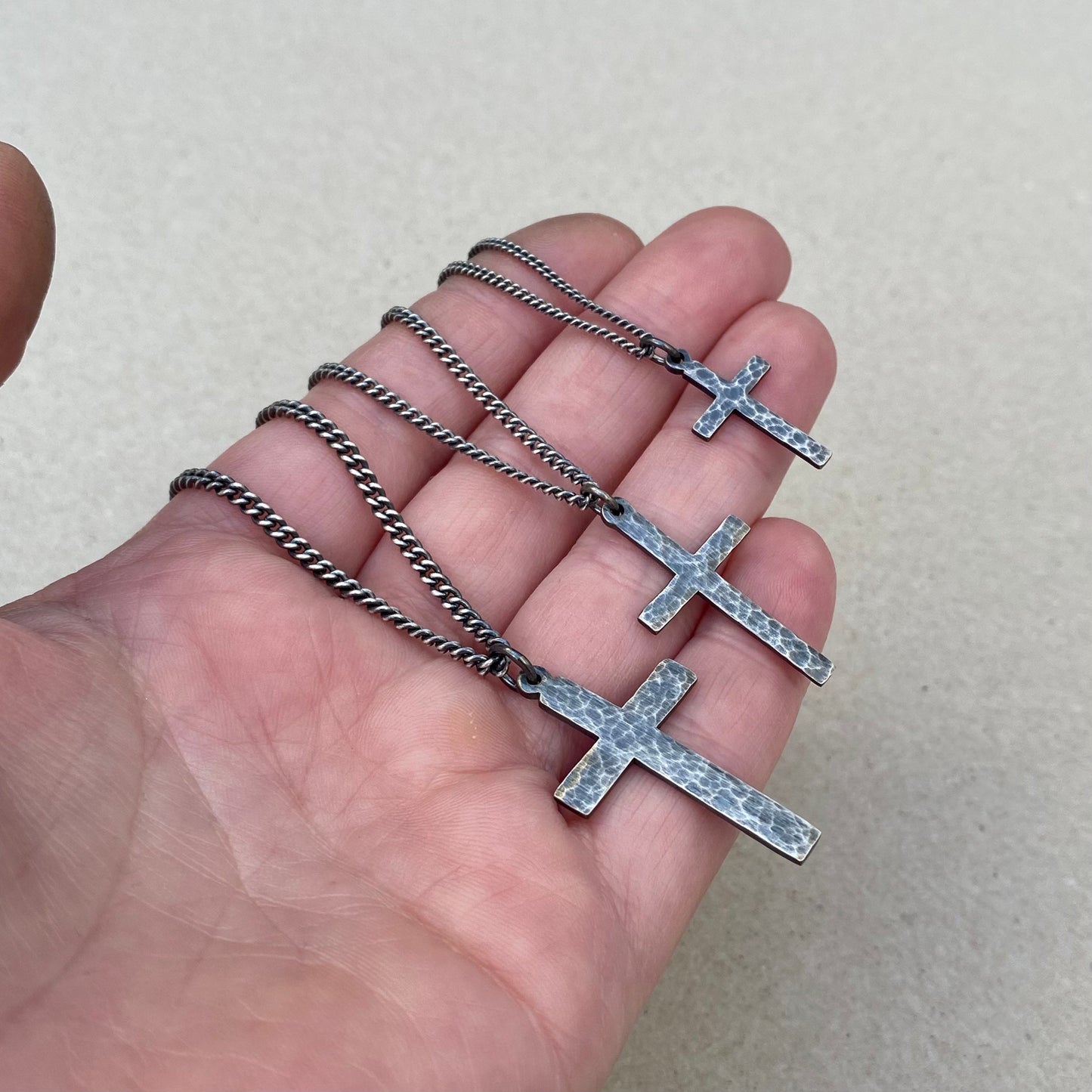 Oxidised or polished solid silver hammered finish small, standard, and medium cross pendants on a curb chain