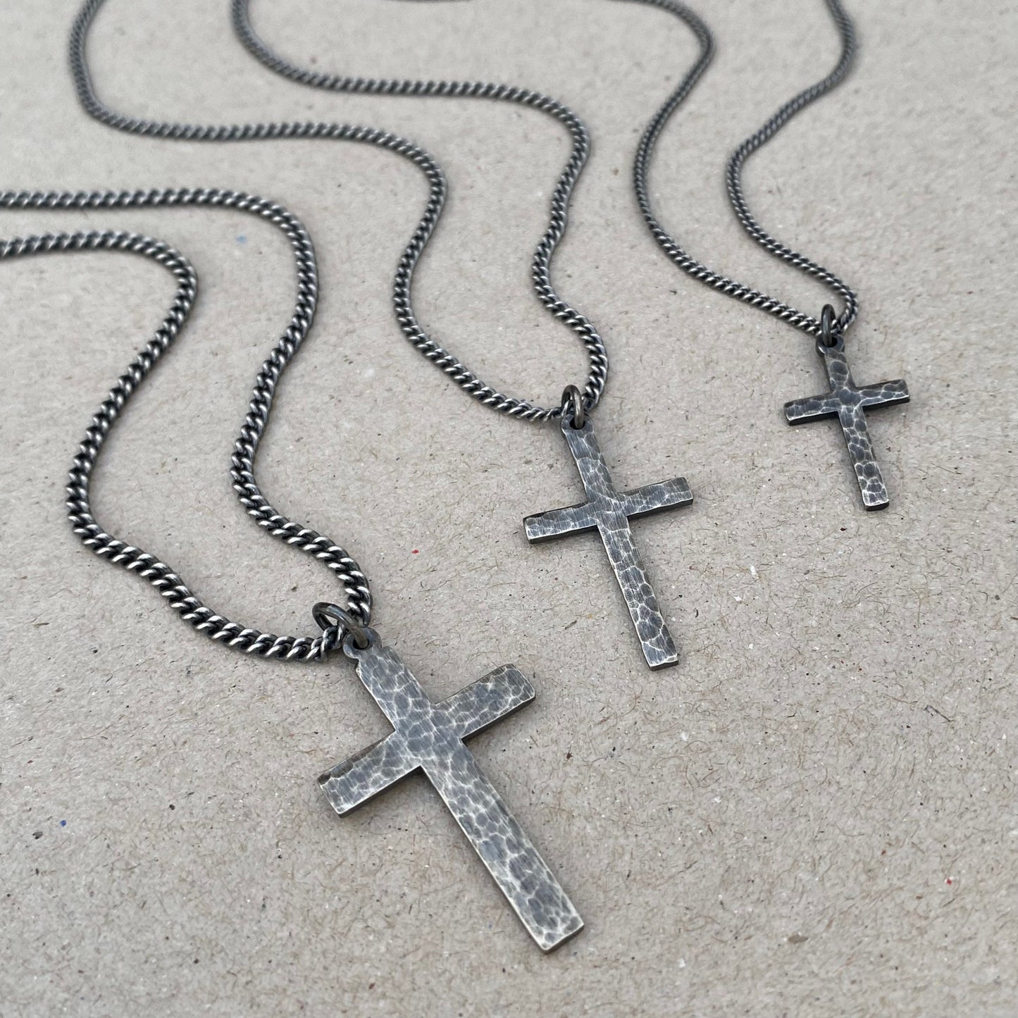 Oxidised or polished solid silver hammered finish small, standard, and medium cross pendants on a curb chain