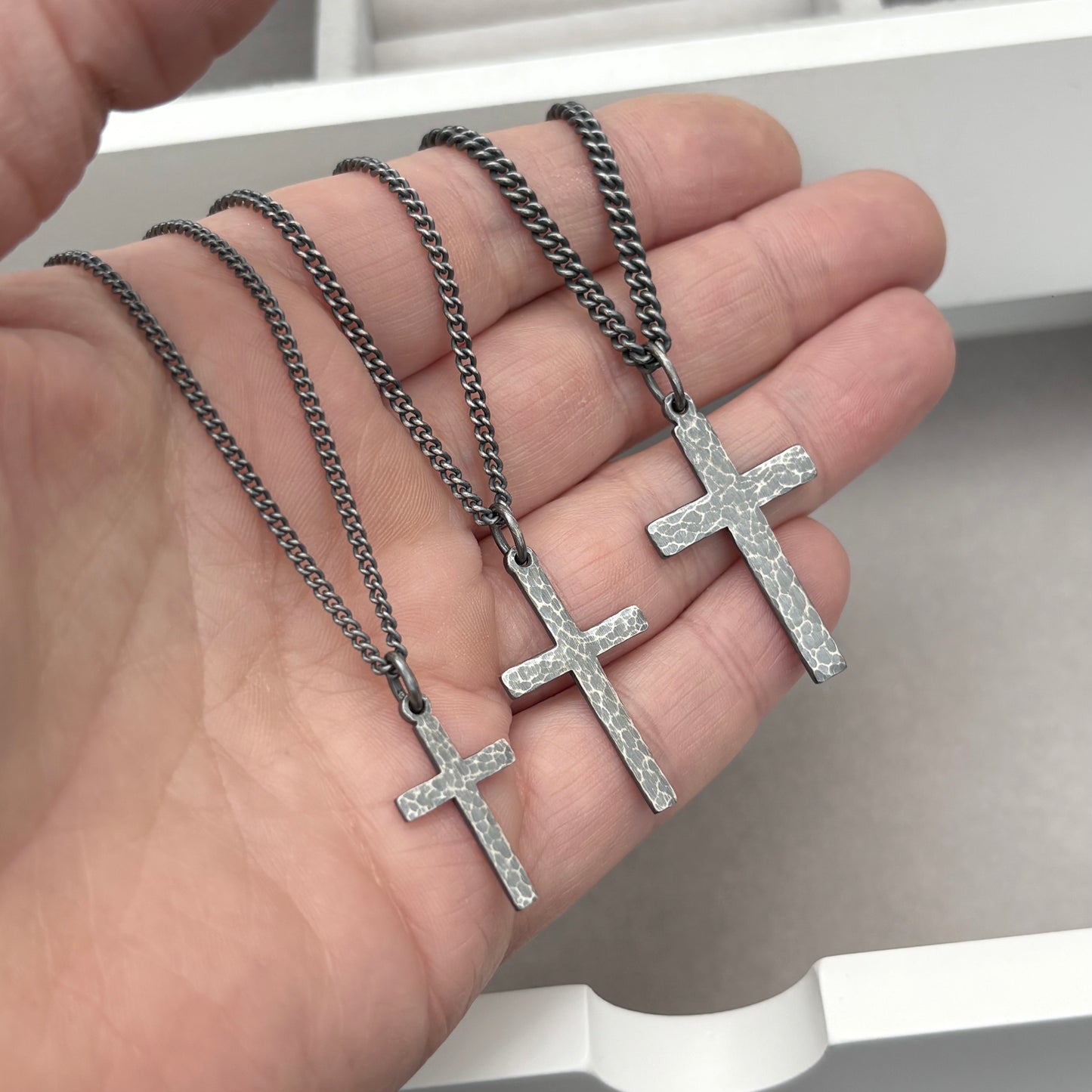 Oxidised sterling silver hammered finish small, standard, and medium cross pendants on a curb chain