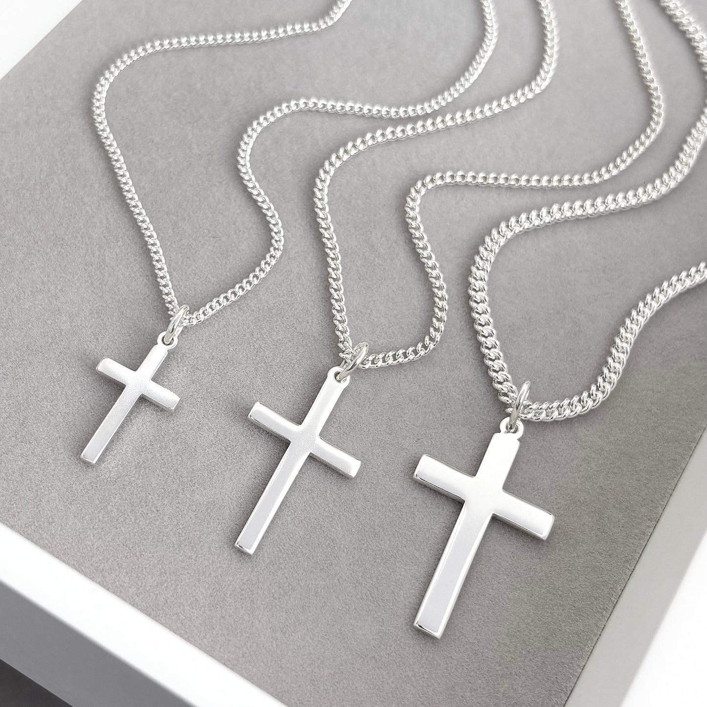 Polished sterling silver plain small, standard, and medium cross pendants on a curb chain
