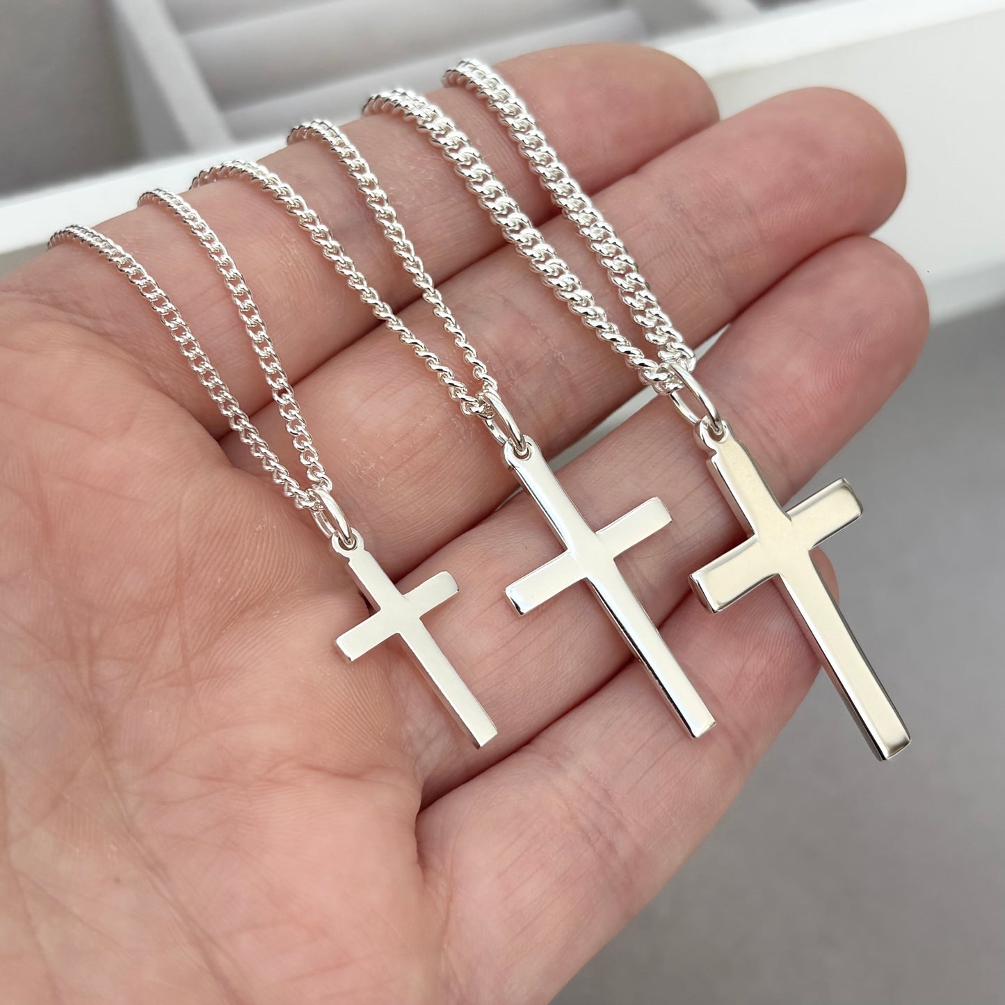 Polished sterling silver plain small, standard, and medium cross pendants on a curb chain