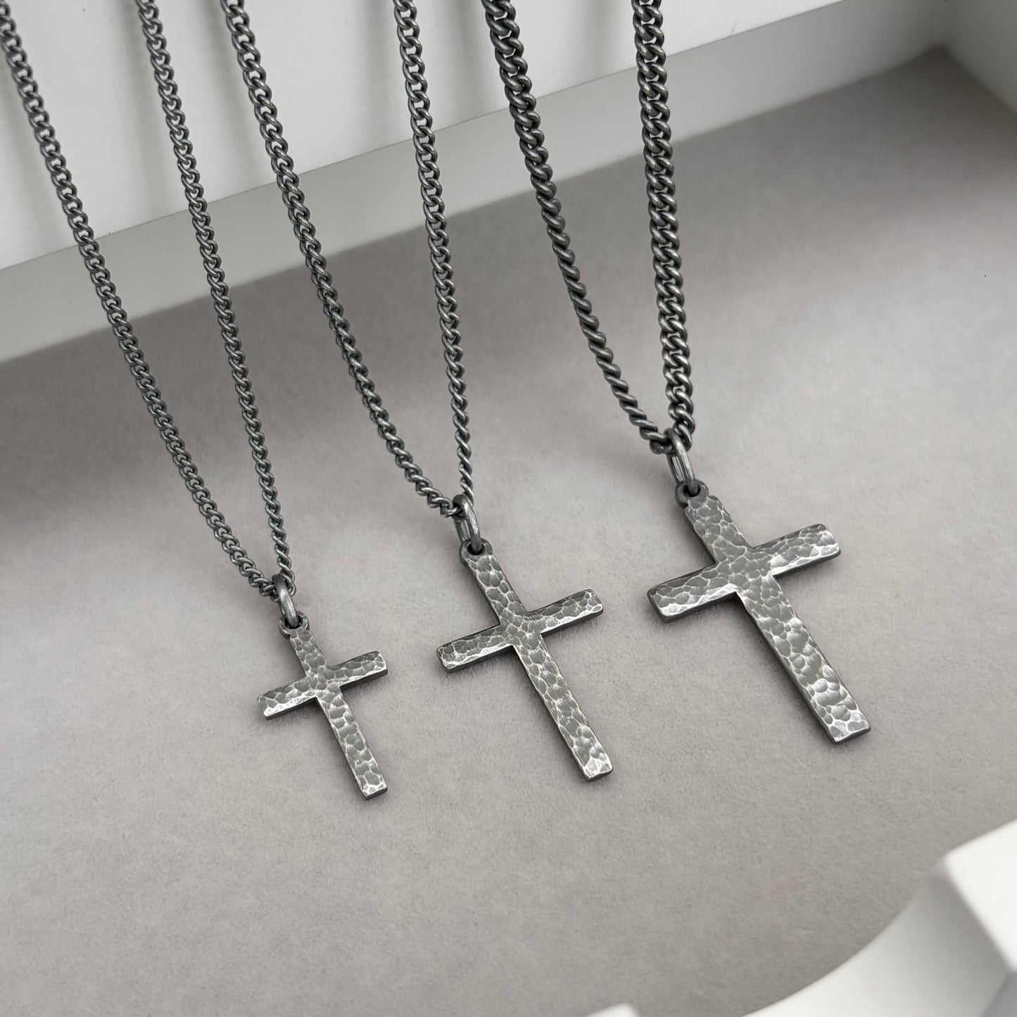 Oxidised sterling silver hammered finish small, standard, and medium cross pendants on a curb chain