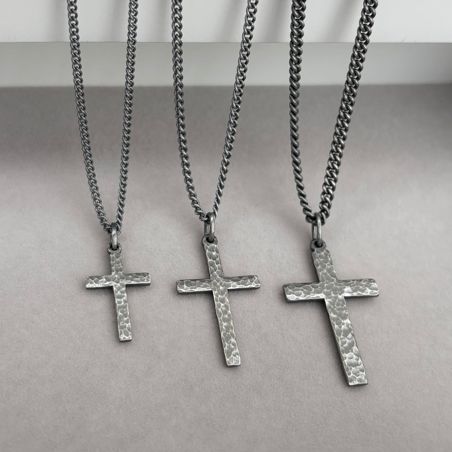 Oxidised sterling silver hammered finish small, standard, and medium cross pendants on a curb chain