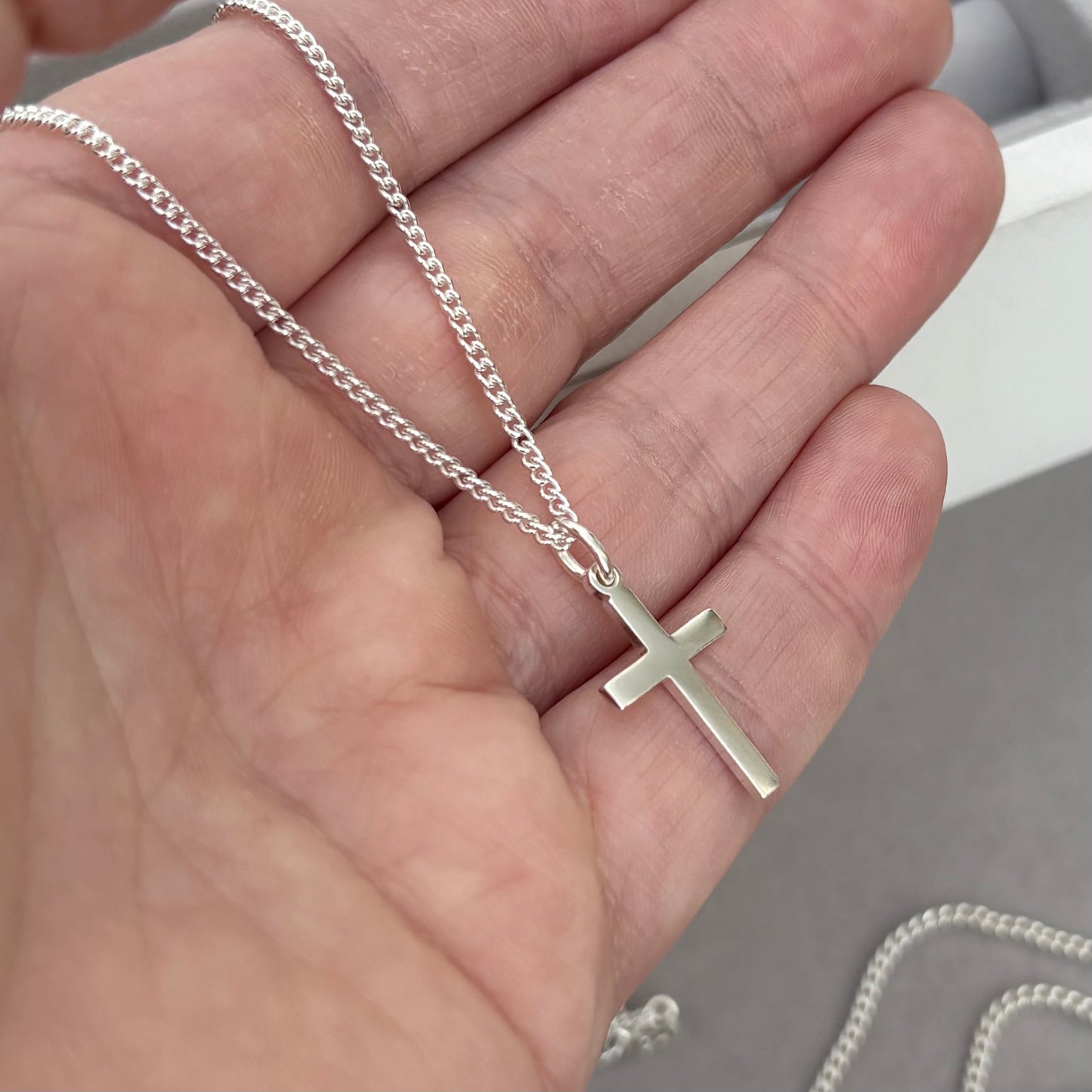Polished sterling silver plain small, standard, and medium cross pendants on a curb chain