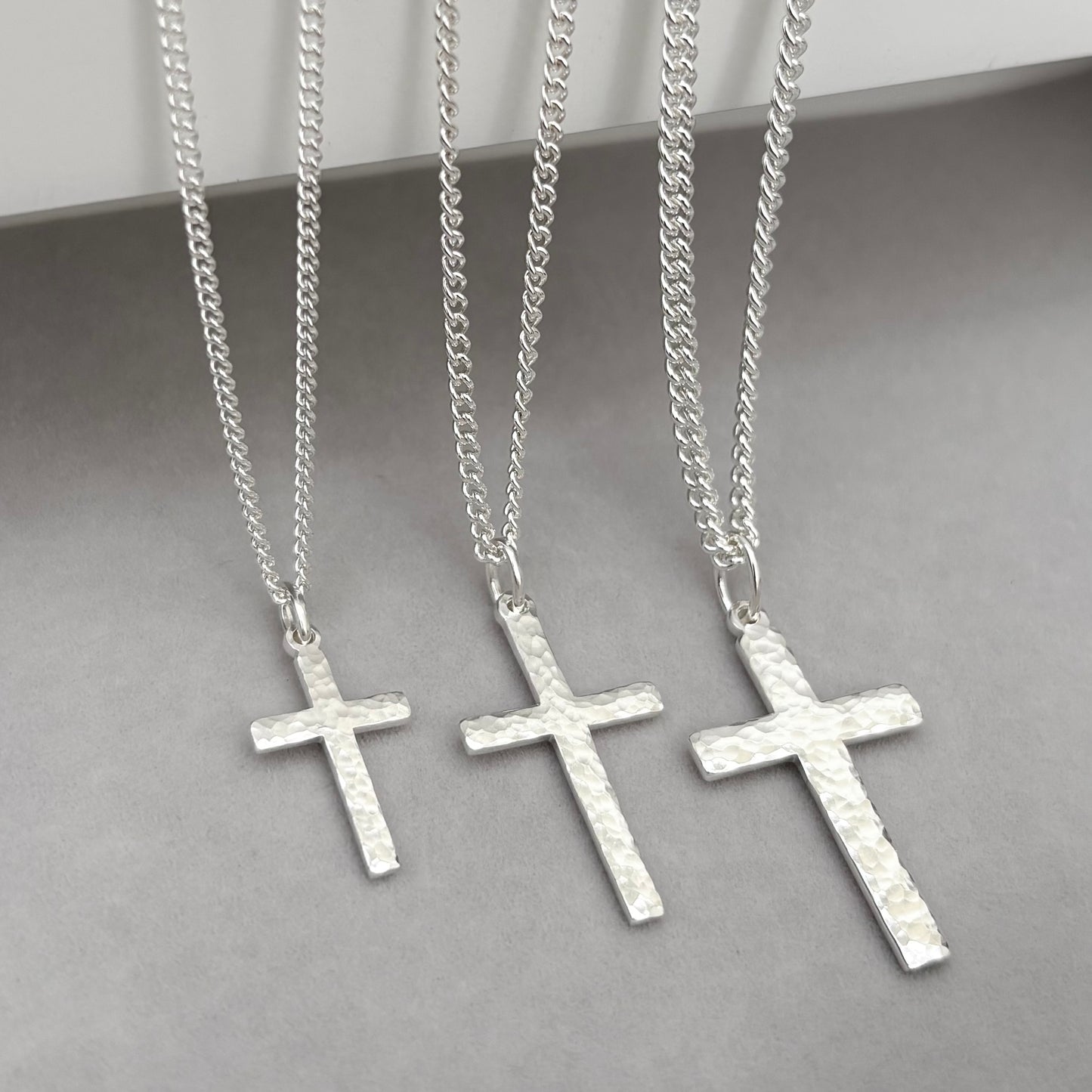 Polished sterling silver hammered finish small, standard, and medium cross pendants on a curb chain