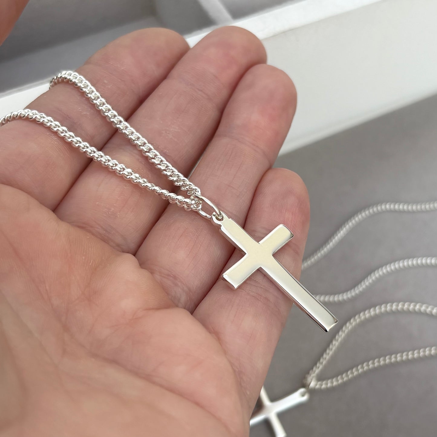 Polished sterling silver plain small, standard, and medium cross pendants on a curb chain