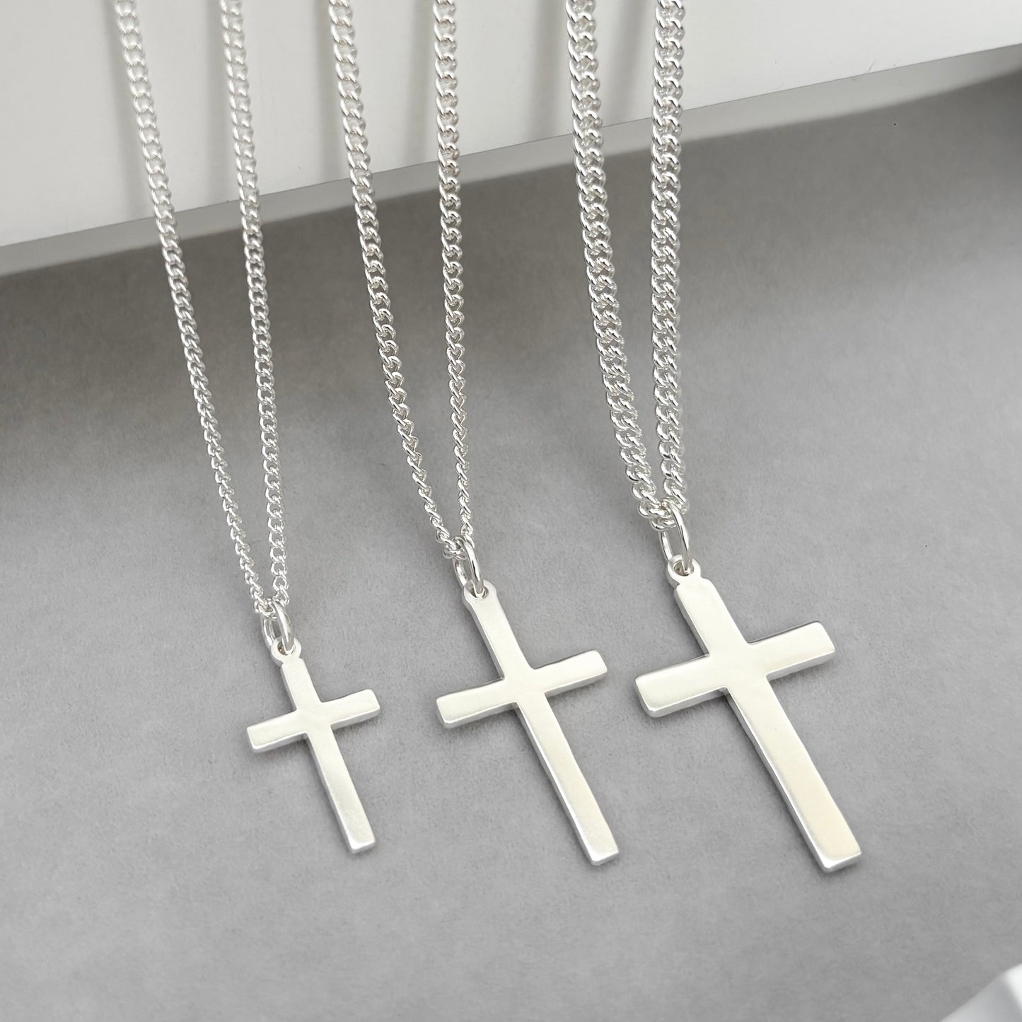Polished sterling silver hammered finish small, standard, and medium cross pendants on a curb chain