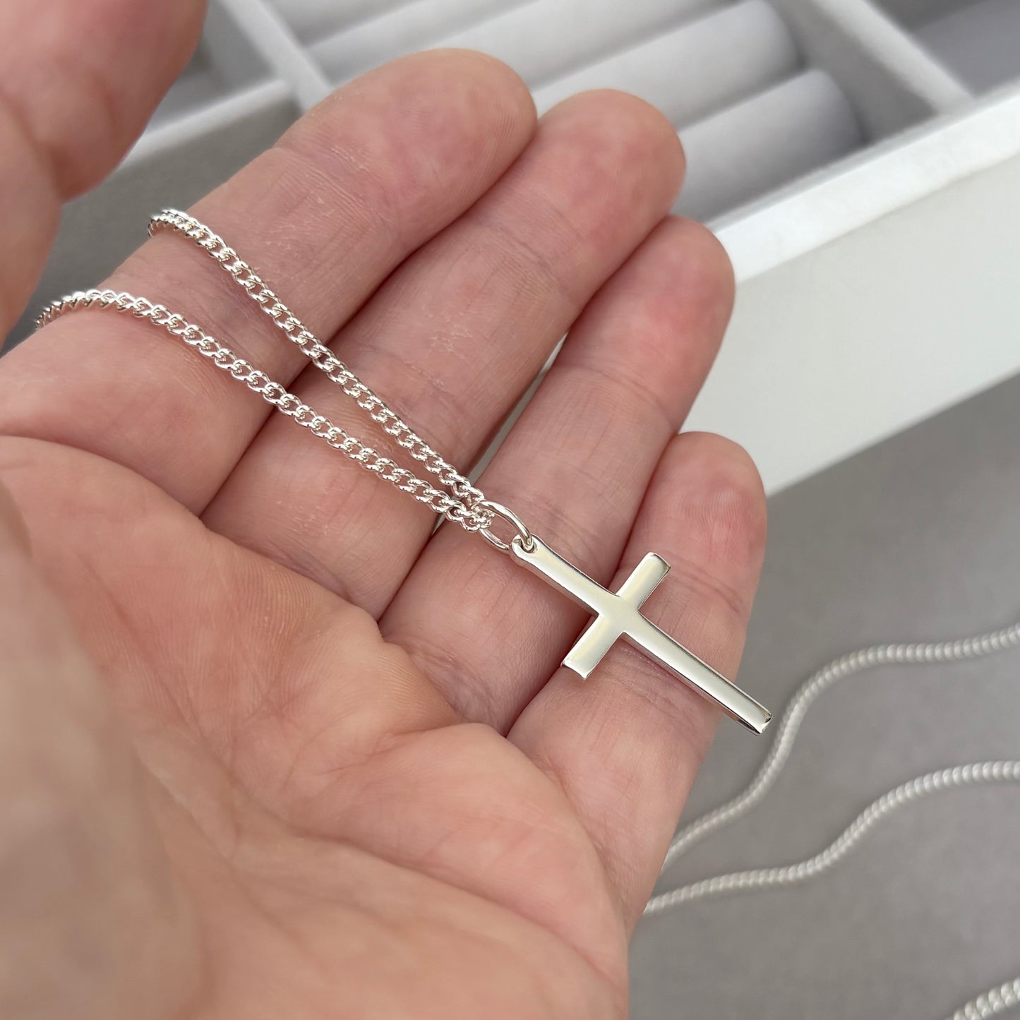 Polished sterling silver plain small, standard, and medium cross pendants on a curb chain