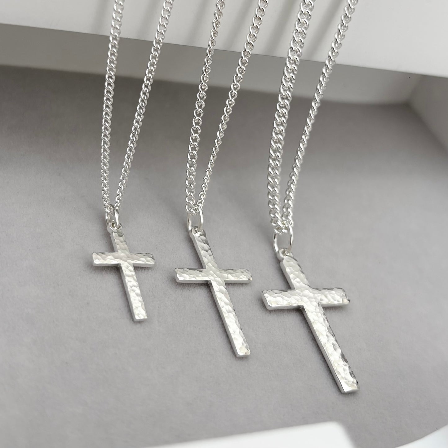 Polished sterling silver hammered finish small, standard, and medium cross pendants on a curb chain
