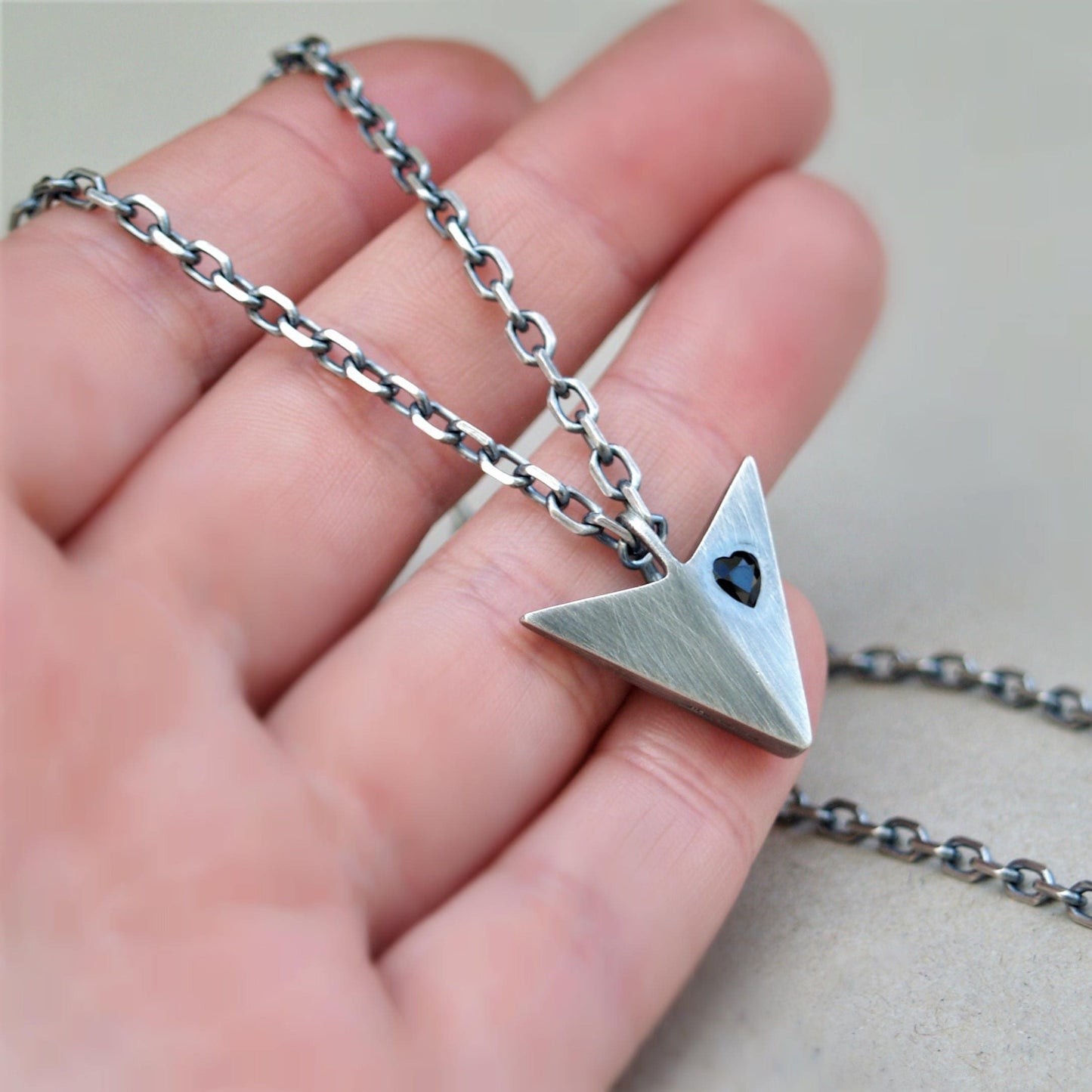 Oxidised solid sterling silver large arrow pendant set with a black sapphire heart on a diamond cut trace chain