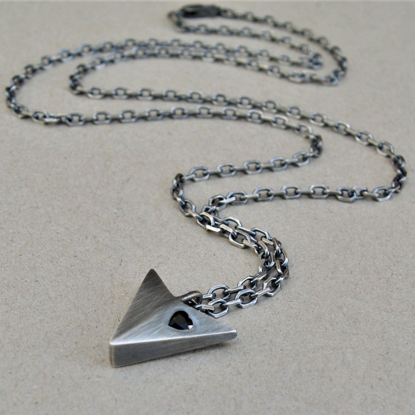 Oxidised solid sterling silver large arrow pendant set with a black sapphire heart on a diamond cut trace chain