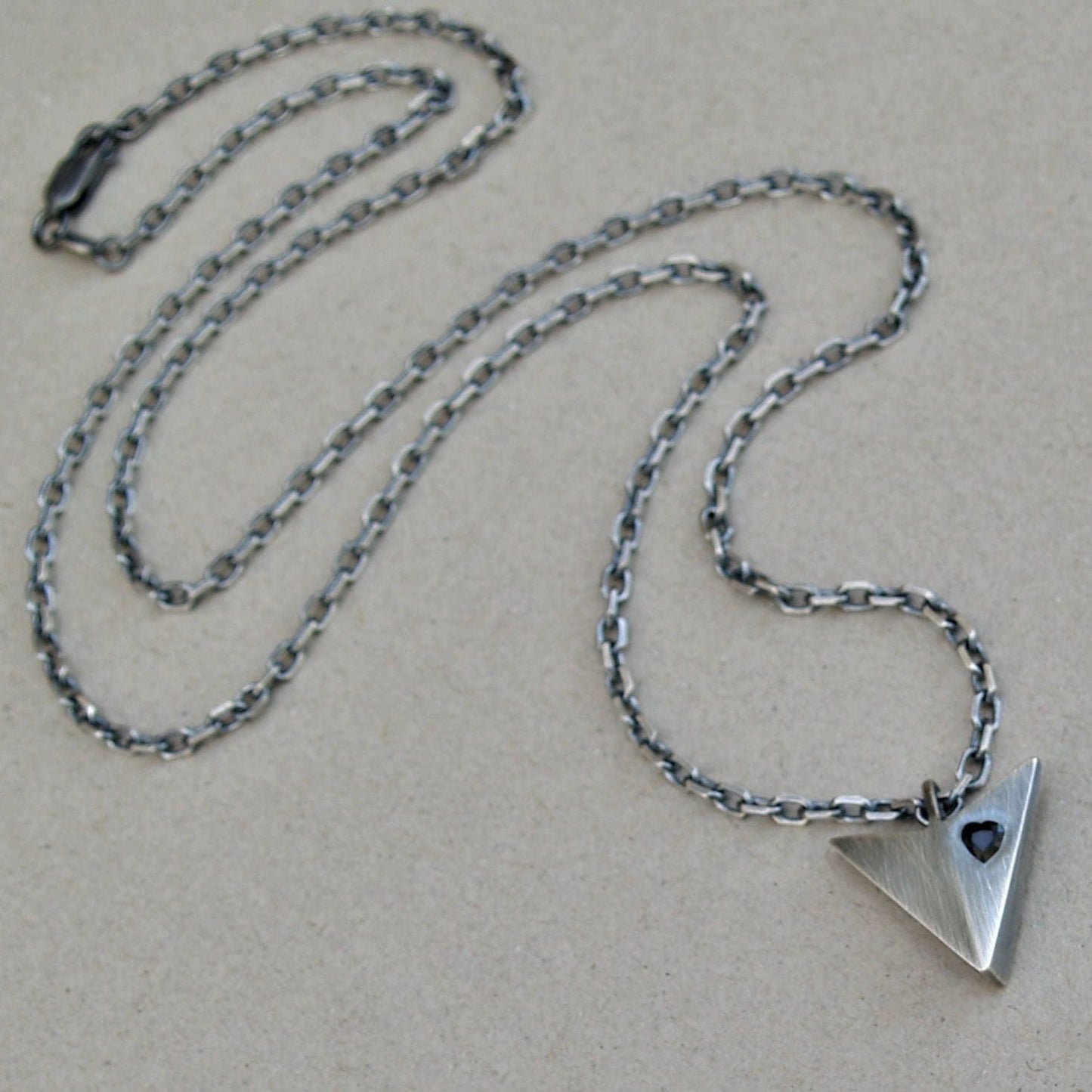 Oxidised solid sterling silver large arrow pendant set with a black sapphire heart on a diamond cut trace chain