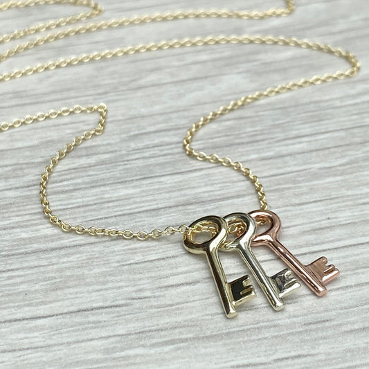 9ct solid yellow, white and rose gold small key pendants on a 9ct yellow gold trace chain