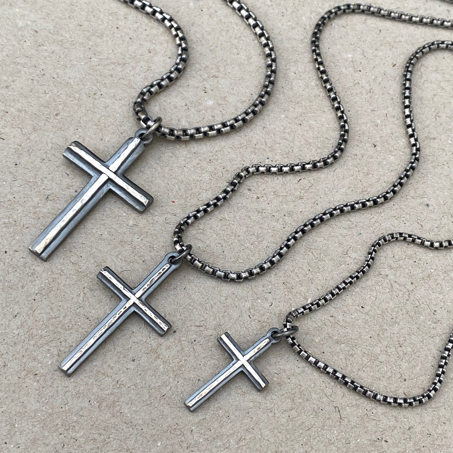 Oxidised solid silver small, standard and medium cross pendants with a polished hammered line detail on a round box chain