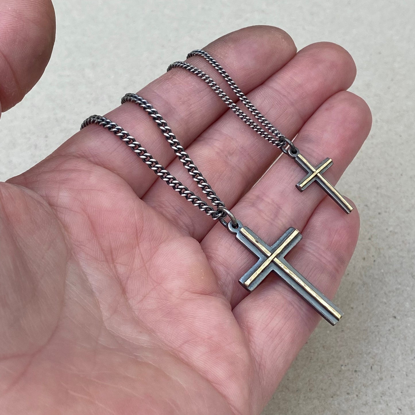 Oxidised solid sterling silver small and medium size cross pendants with a polished hammered 9ct yellow gold line detail on a curb chain