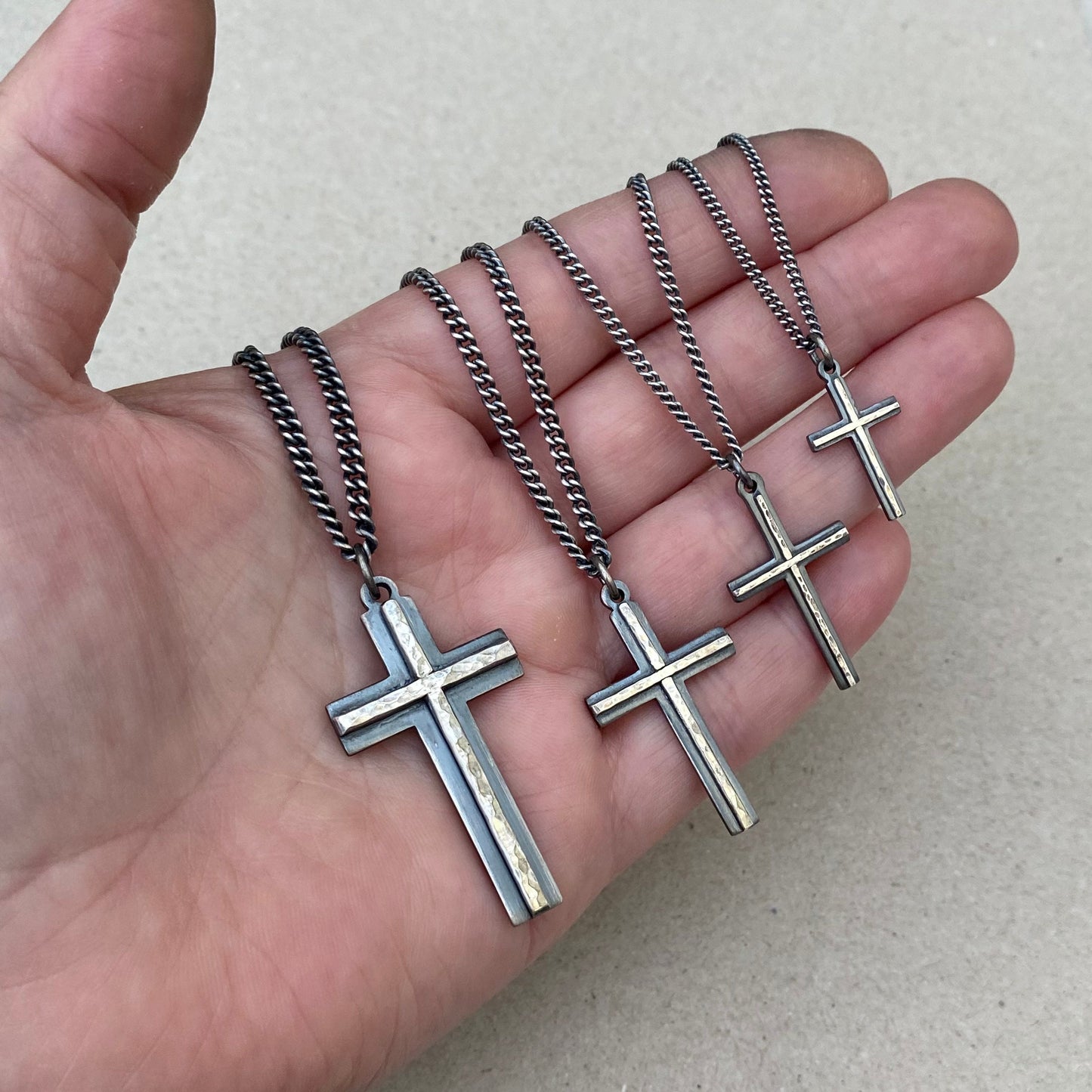 Oxidised solid sterling silver small, standard, medium and large cross pendants with a polished hammered line detail on a curb chain