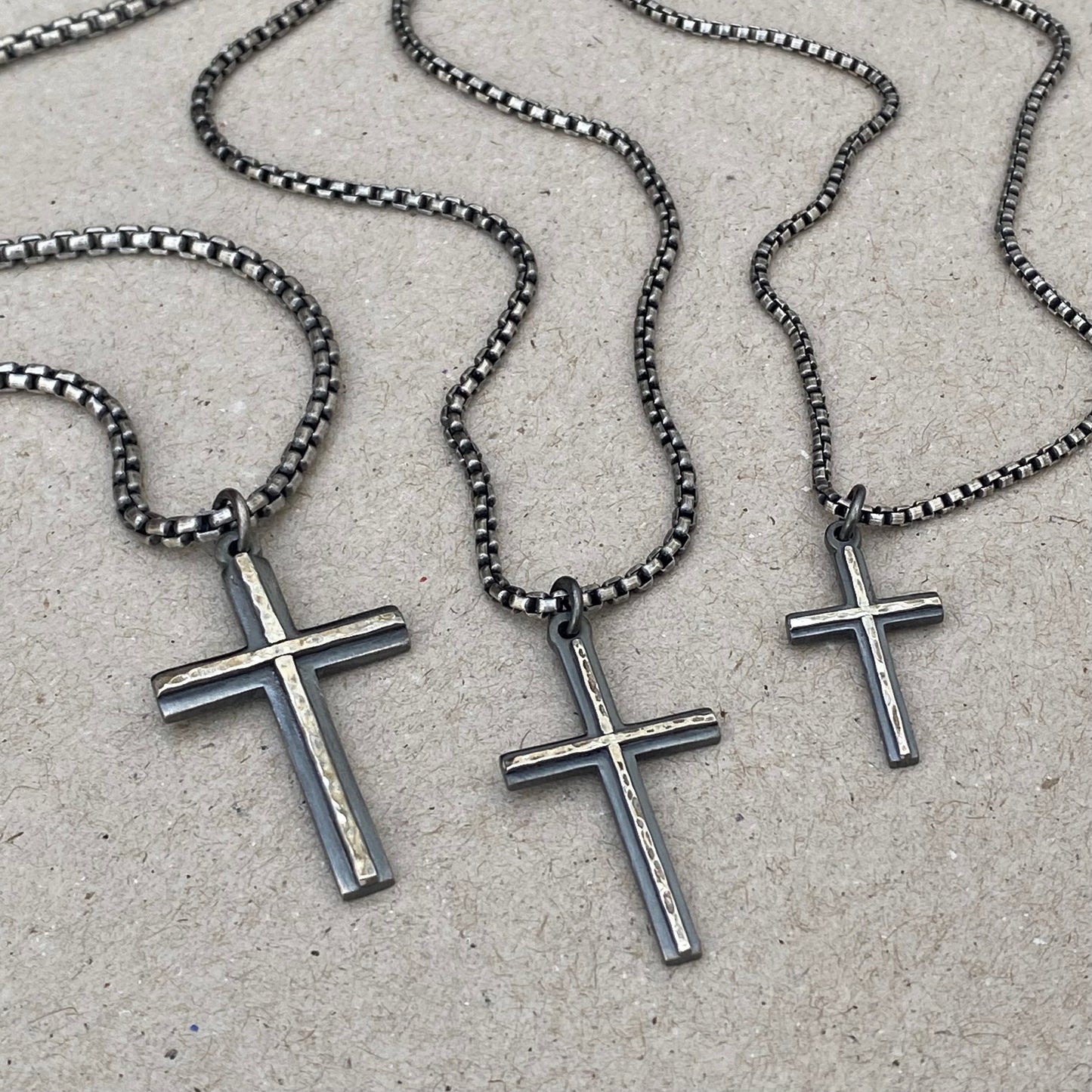 Oxidised solid silver small, standard and medium cross pendants with a polished hammered line detail on a round box chain
