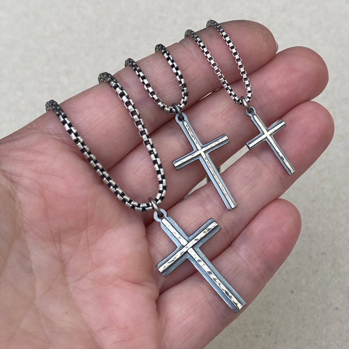 Oxidised solid silver small, standard and medium cross pendants with a polished hammered line detail on a round box chain