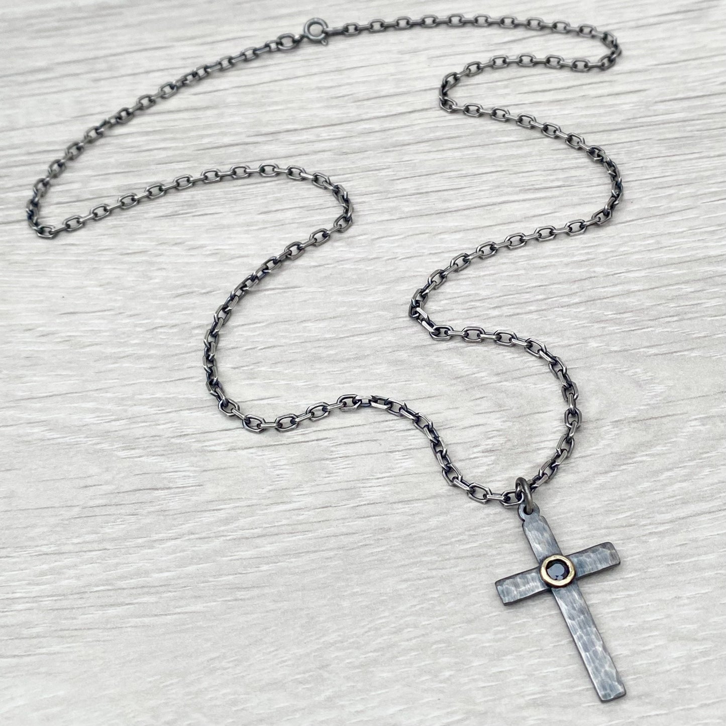 Oxidised solid sterling silver hammered medium size cross with a 9ct yellow gold set black sapphire on a diamond cut trace chain