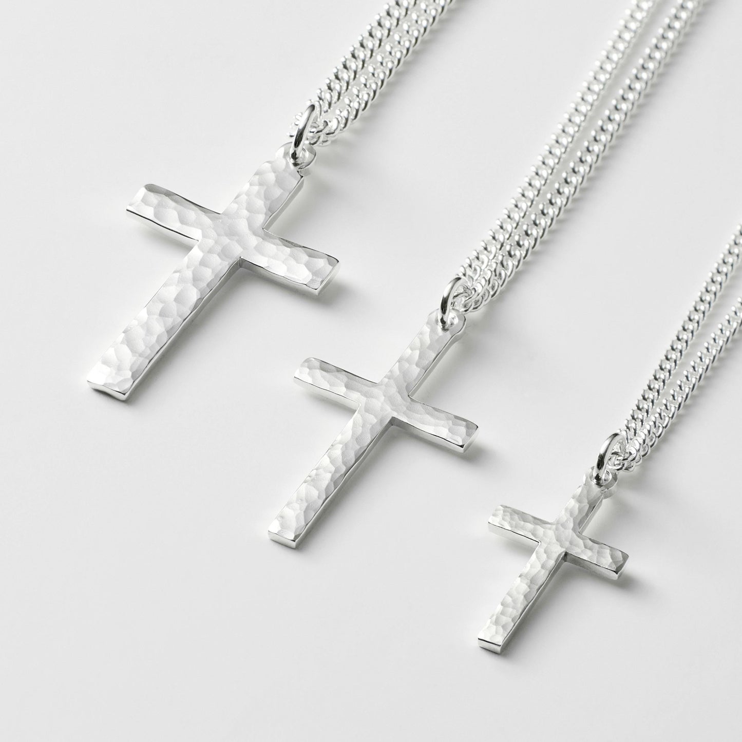Oxidised or polished solid silver hammered finish small, standard, and medium cross pendants on a curb chain