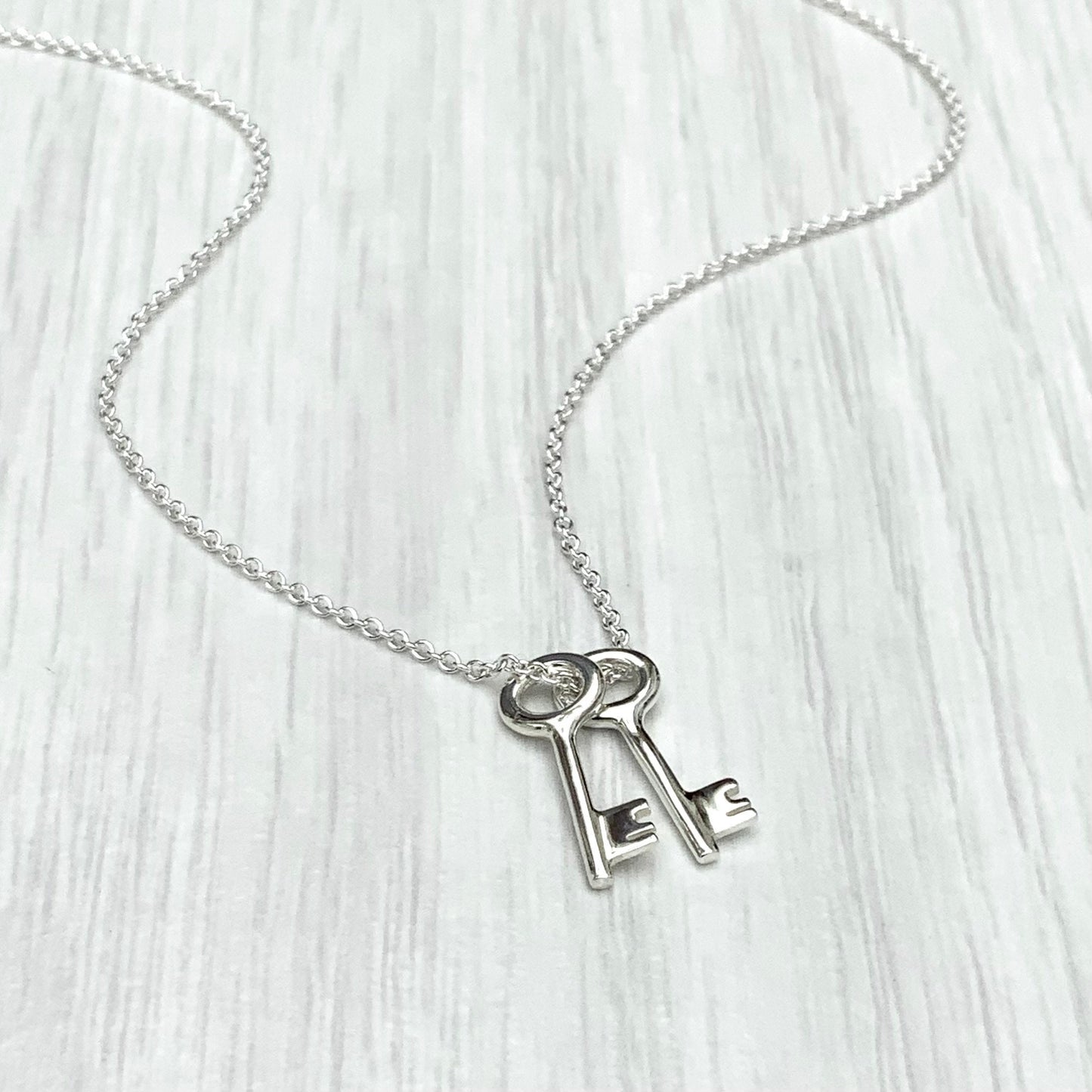 Solid silver small and dainty key charm pendants on a trace chain. A choice of one, two or three key pendants.